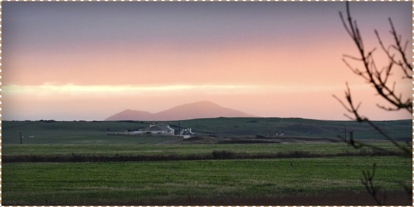 This is a picture of the view from our luxury bed and breakfast in Anglesey, looking out towards the mountains at sunset. It is being used as a blog header.
